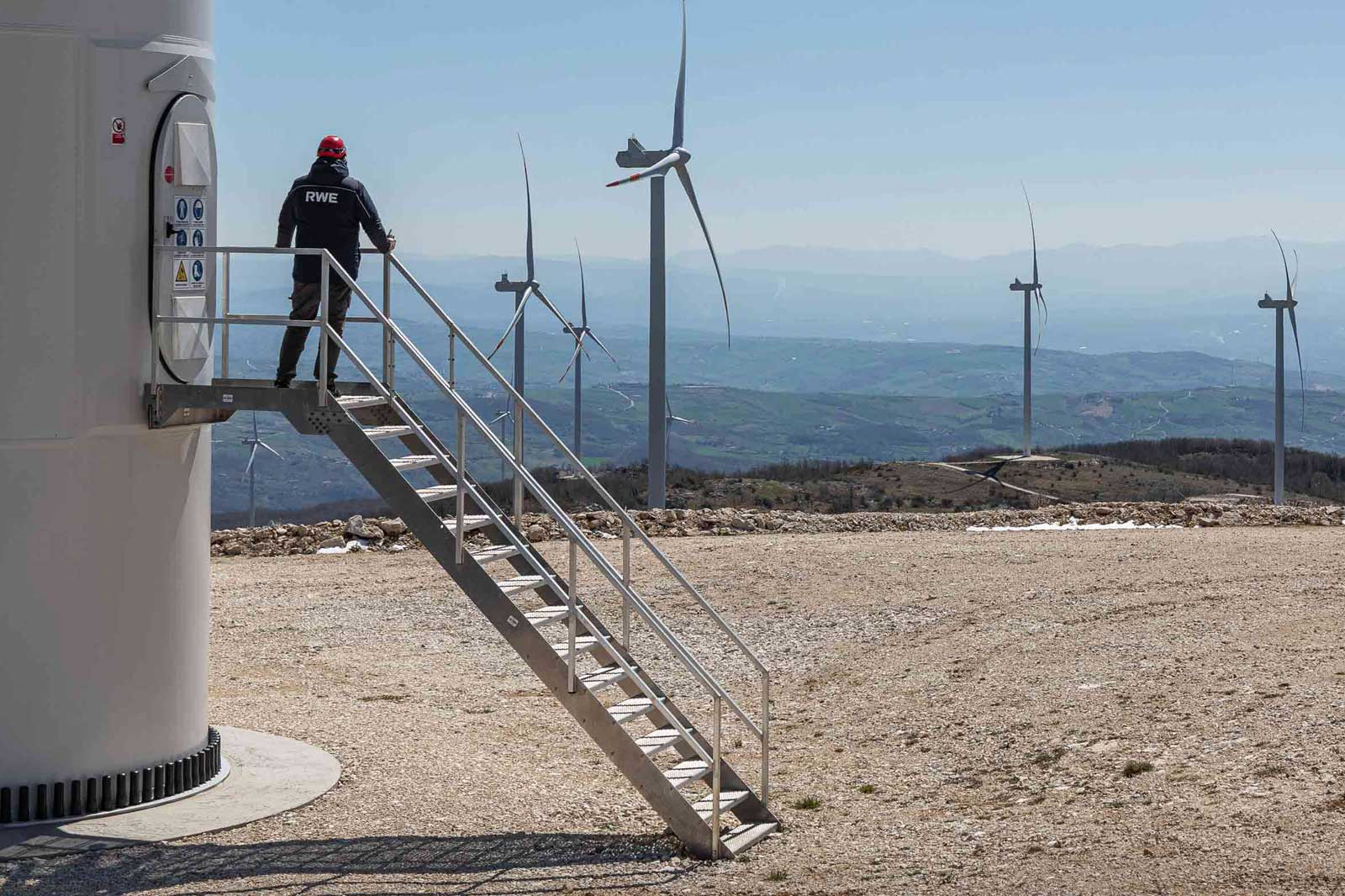 Ein Mann steht vor dem Fuß einer Onshore Windanlage | Erneuerbare Energien bei RWE entdecken